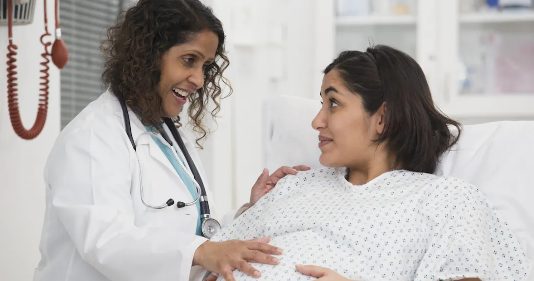 A pregnant woman talking with a doctor in a hospital. A pregnant woman talking with a doctor in a hospital.