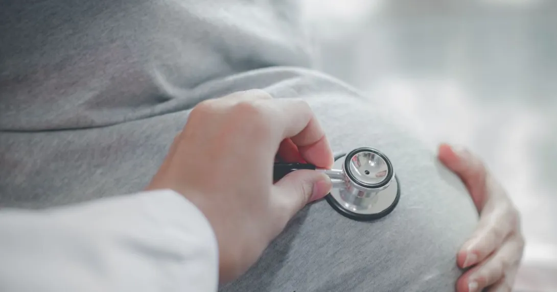 A health professional placing a stethoscope on a pregnant belly A health professional placing a stethoscope on a pregnant belly