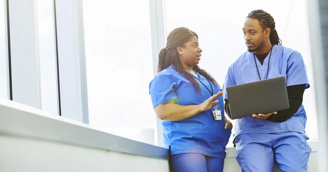 A doctor showing his colleague information on a laptop A doctor showing his colleague information on a laptop
