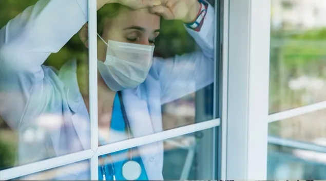 Tired doctor looking out of window