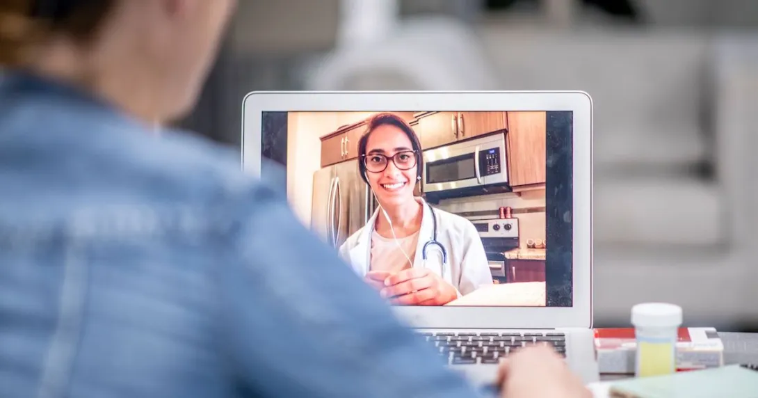 A person talking a doctor via a video chat on their laptop. A person talking a doctor via a video chat on their laptop.