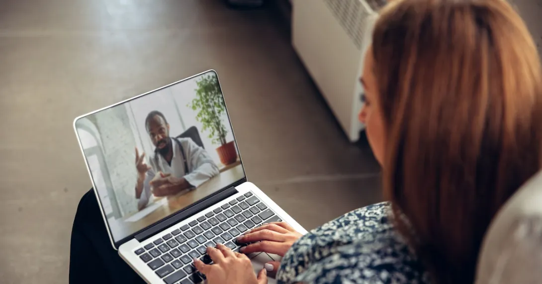 A person talking to a doctor via a video chat on a laptop.