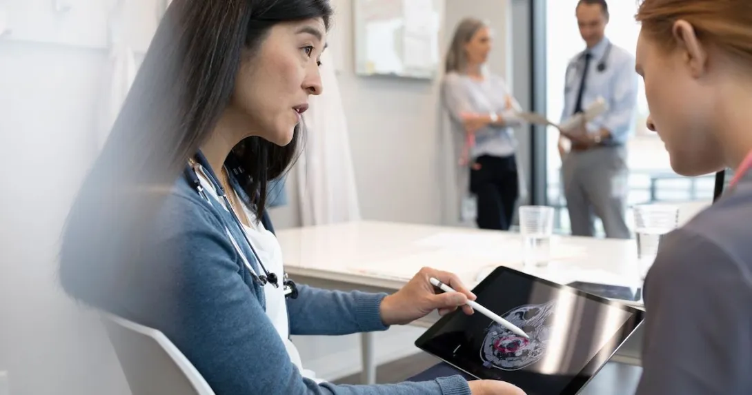 Two people looking at a tablet with an ultrasound image of a brain on the screen Two people looking at a tablet with an ultrasound image of a brain on the screen