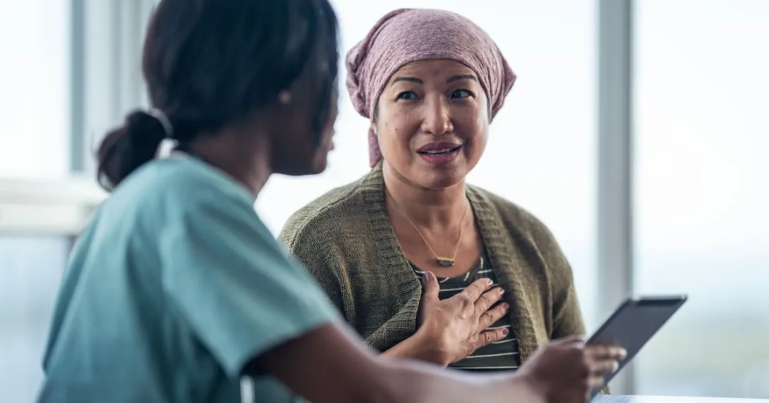 Healthcare provider sitting next to a patient while both look at a tablet Healthcare provider sitting next to a patient while both look at a tablet