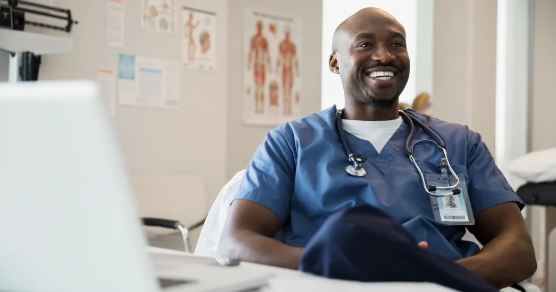 Healthcare provider sitting at a desk while wearing scrubs Healthcare provider sitting at a desk while wearing scrubs