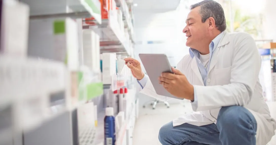 Pharmacy worker looking at shelves with medications on them Pharmacy worker looking at shelves with medications on them
