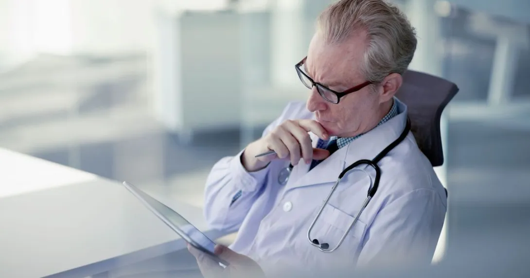 Physician sitting in a chair looking at a tablet Physician sitting in a chair looking at a tablet