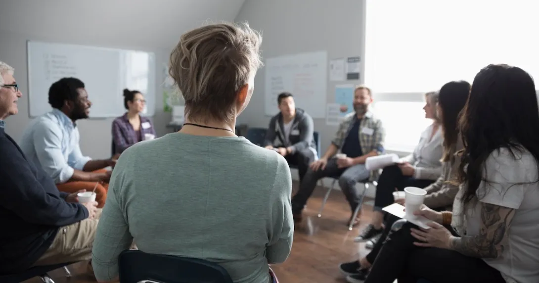 Group of people sitting in a room in a circle Group of people sitting in a room in a circle