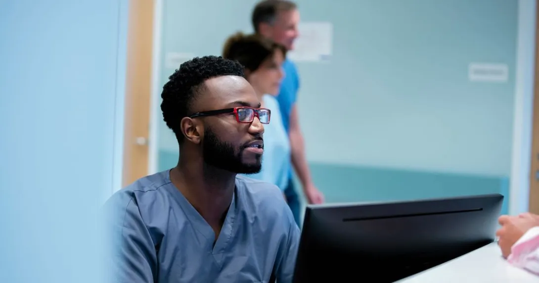 Healthcare provider in scrubs sitting at a computer Healthcare provider in scrubs sitting at a computer