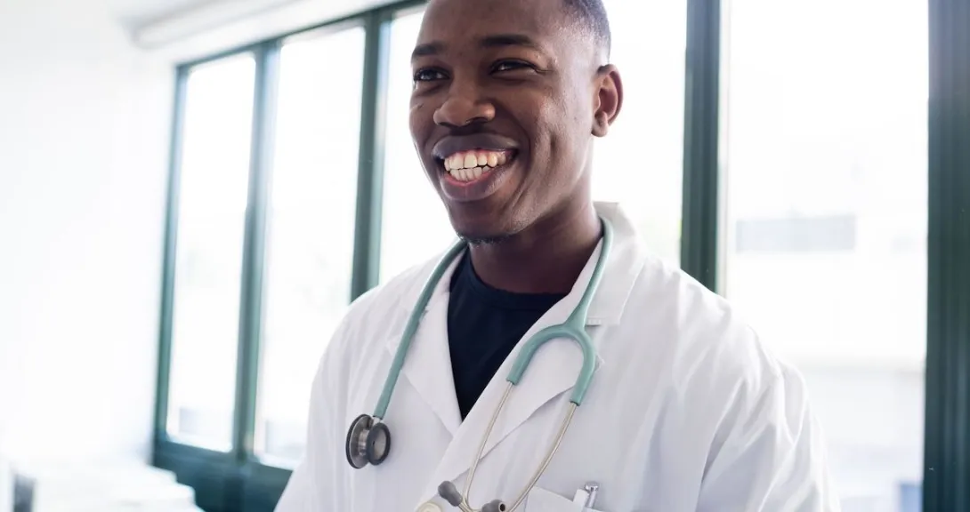 Healthcare provider smiling while wearing a lab coat and stethoscope Healthcare provider smiling while wearing a lab coat and stethoscope