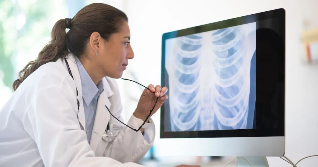 Healthcare provider sitting down and looking at a computer screen with diagnostic images on it