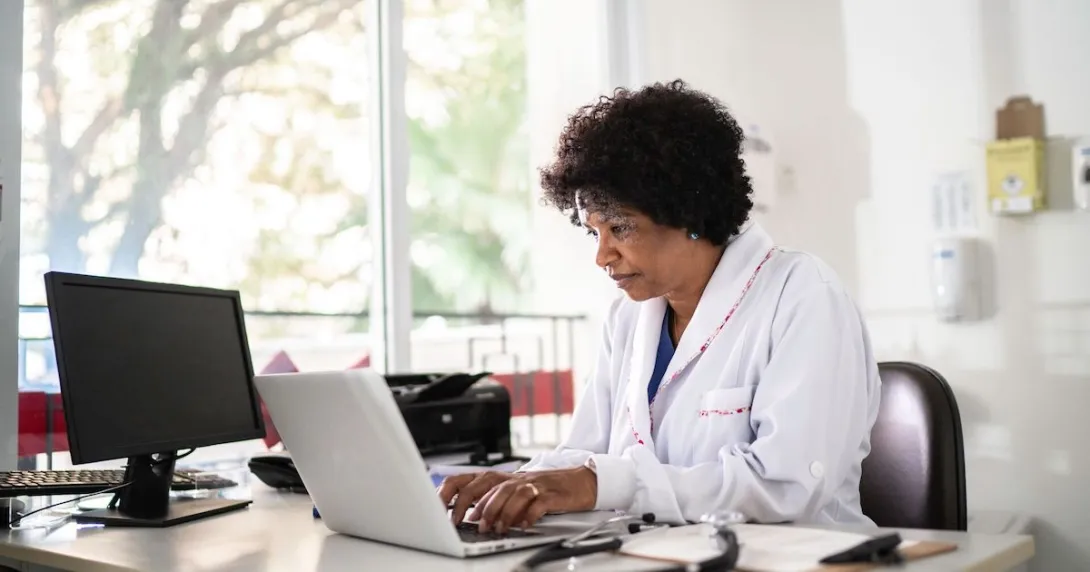 Healthcare provider sitting in an office at a desk with a computer on it Healthcare provider sitting in an office at a desk with a computer on it