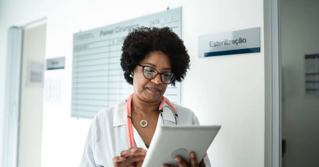 Healthcare provider on a tablet walking through a clinic Healthcare provider on a tablet walking through a clinic