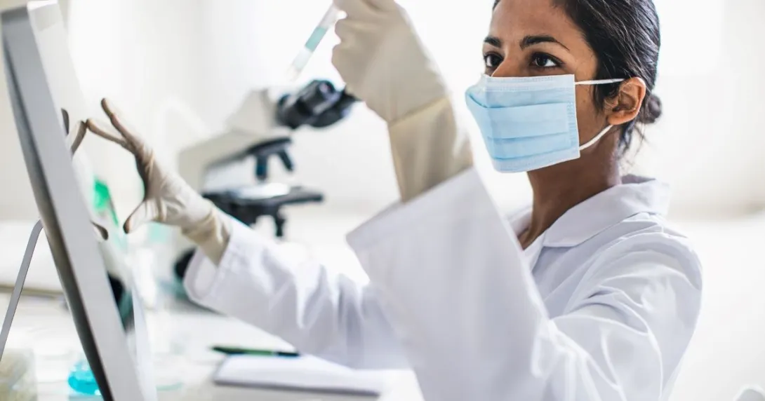 Person wearing mask holding test tube Person wearing mask holding test tube