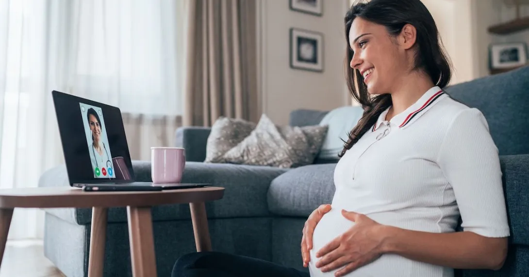 Pregnant person sitting on the floor looking at a computer Pregnant person sitting on the floor looking at a computer