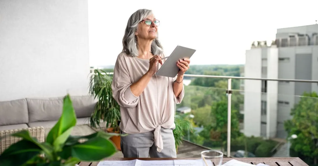 Person standing on a balcony with a tablet in their hand Person standing on a balcony with a tablet in their hand