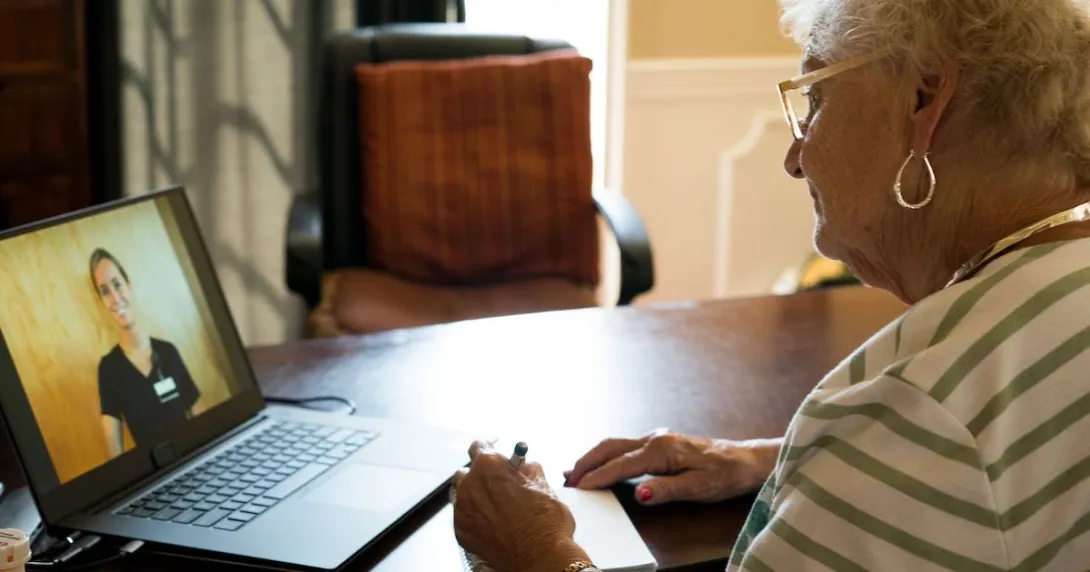 Person sitting at a table with a laptop on it, talking to a healthcare provider via the computer Person sitting at a table with a laptop on it, talking to a healthcare provider via the computer