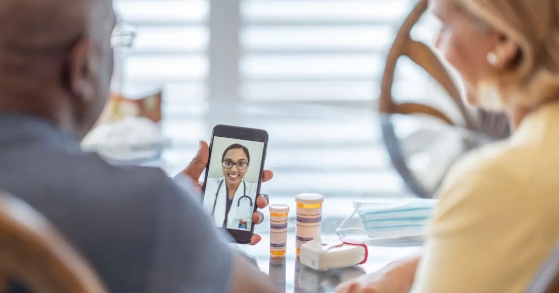 Two people on a telehealth call with medication on the table Two people on a telehealth call with medication on the table