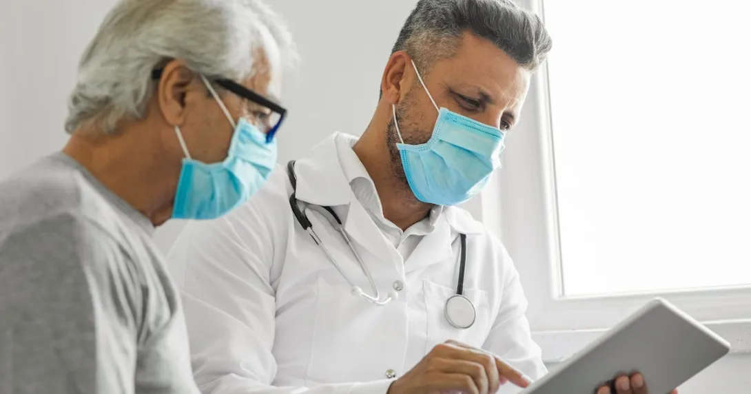 Healthcare provider and patient sitting next to each other while looking at a tablet Healthcare provider and patient sitting next to each other while looking at a tablet