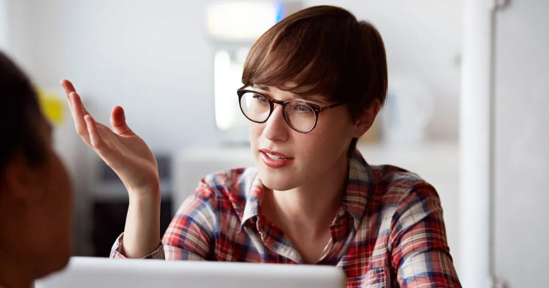 Person on a laptop speaking with someone and wearing glasses Person on a laptop speaking with someone and wearing glasses