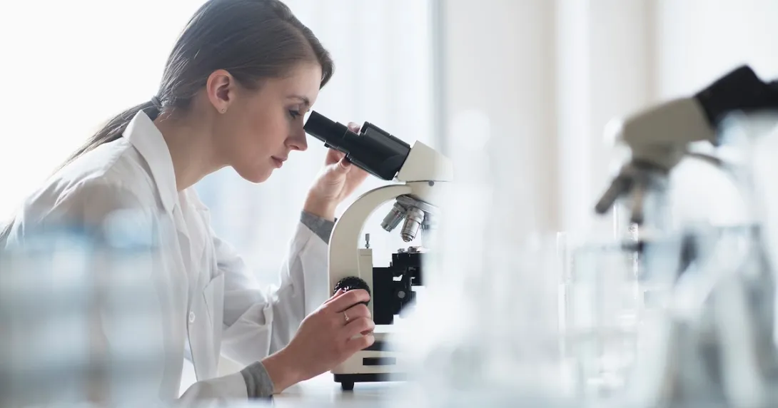 Healthcare professional looking into a microscope Healthcare professional looking into a microscope