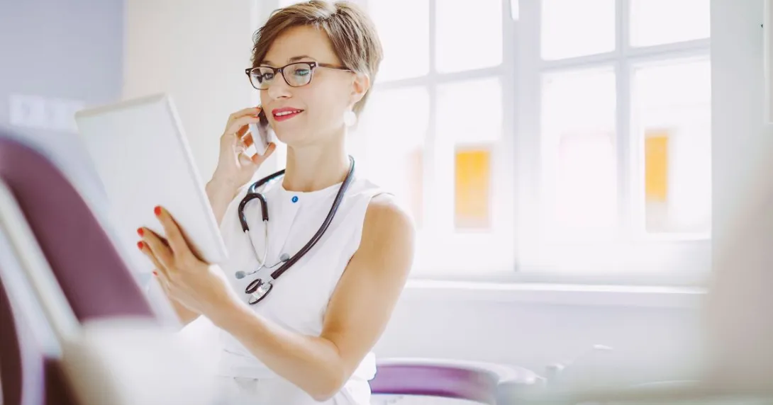 Healthcare provider wearing a white shirt and looking at a tablet Healthcare provider wearing a white shirt and looking at a tablet