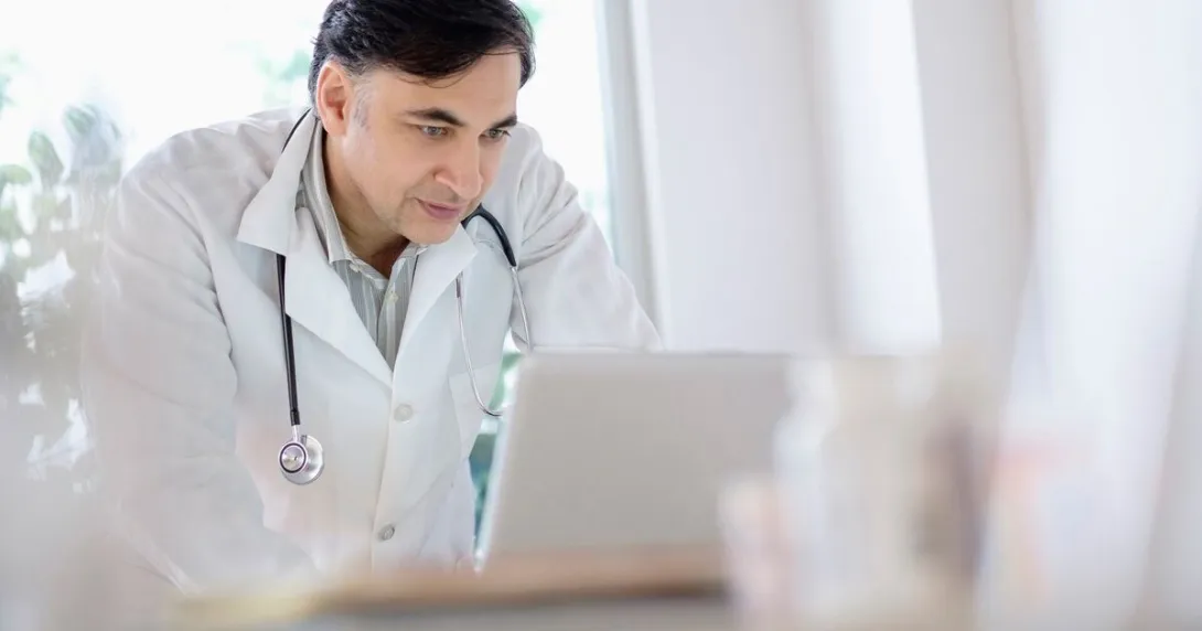 A doctor using a laptop to write referrals A doctor using a laptop to write referrals