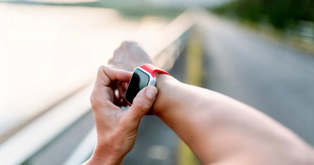 A person wearing a wearable device on their right wrist and touching the device with their left hand A person wearing a wearable device on their right wrist and touching the device with their left hand