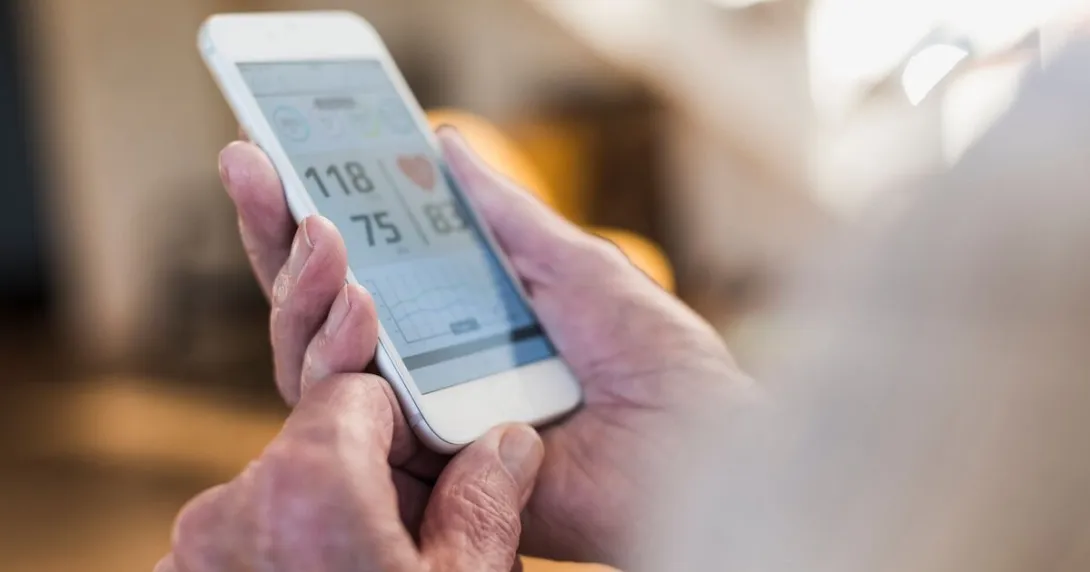 An individual holding a mobile phone showing their heart rate An individual holding a mobile phone showing their heart rate