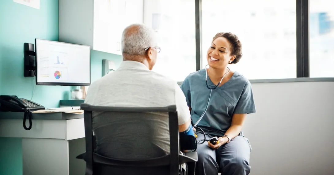 Healthcare provider sitting with a patient near a desk Healthcare provider sitting with a patient near a desk