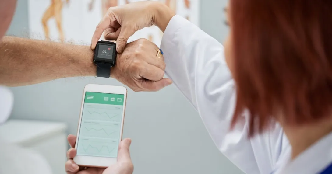 A doctor synchronising a patient's smartwatch with their mobile app A doctor synchronising a patient's smartwatch with their mobile app