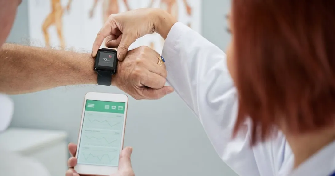 A doctor helping a patient synchronise their smartwatch with a mobile health app