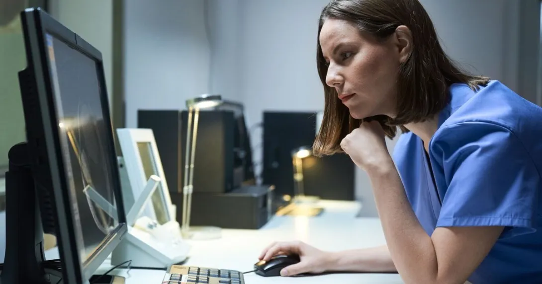 A clinician reading a report from a desktop computer. A clinician reading a report from a desktop computer.