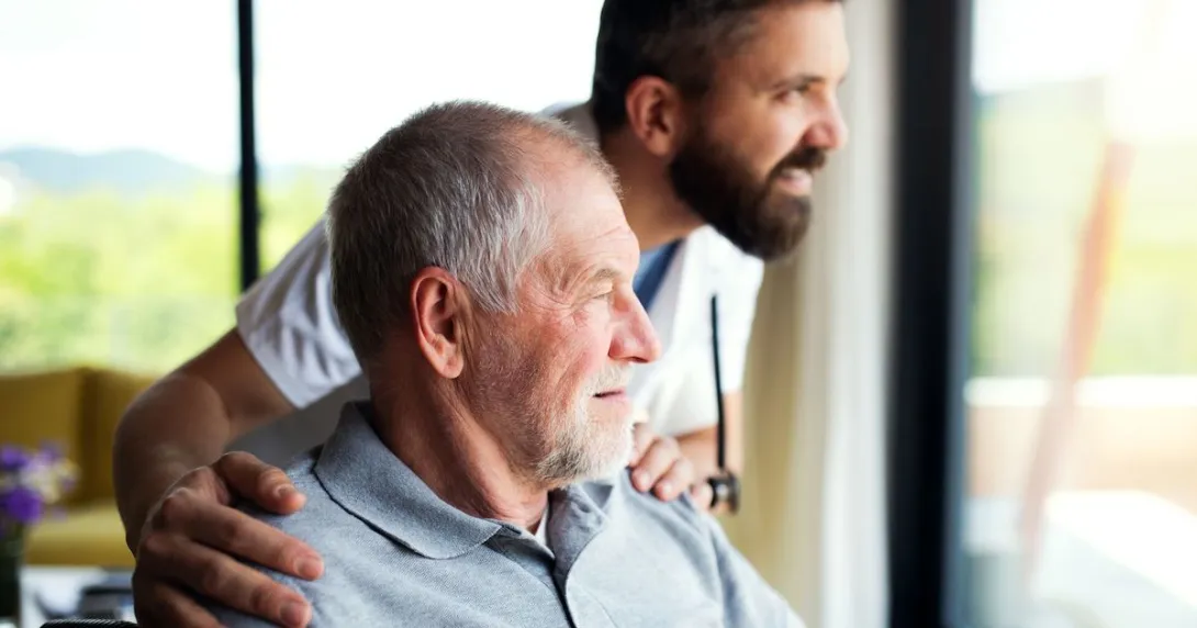 A senior patient and a caregiver looking out the window A senior patient and a caregiver looking out the window