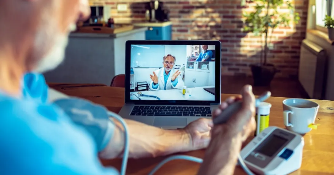 A doctor on screen guiding a patient measuring their blood pressure remotely A doctor on screen guiding a patient measuring their blood pressure remotely