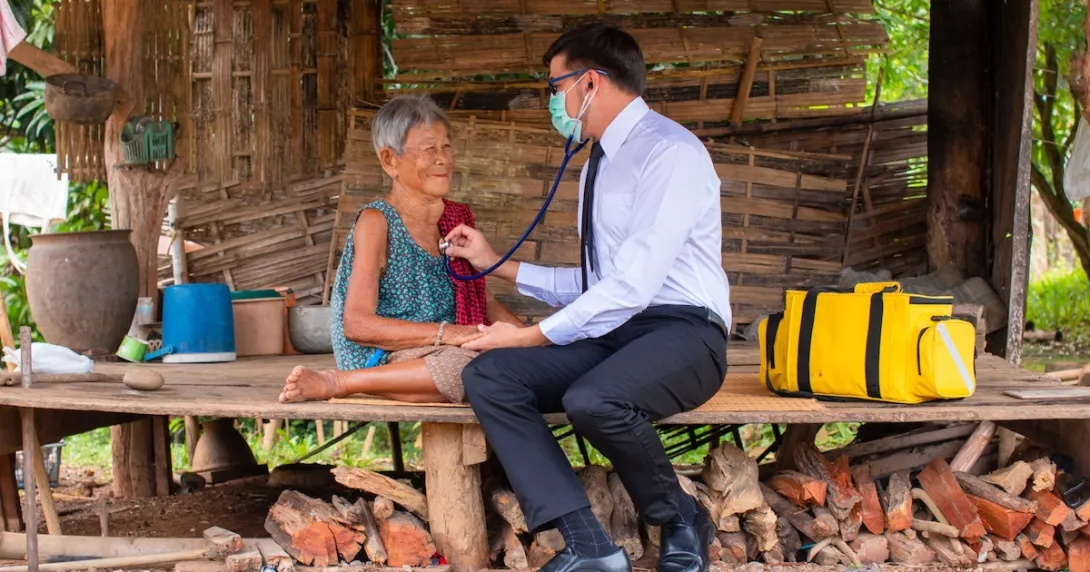 A rural doctor checking an elderly person's breathing with a stethoscope in a hut A rural doctor checking an elderly person's breathing with a stethoscope in a hut